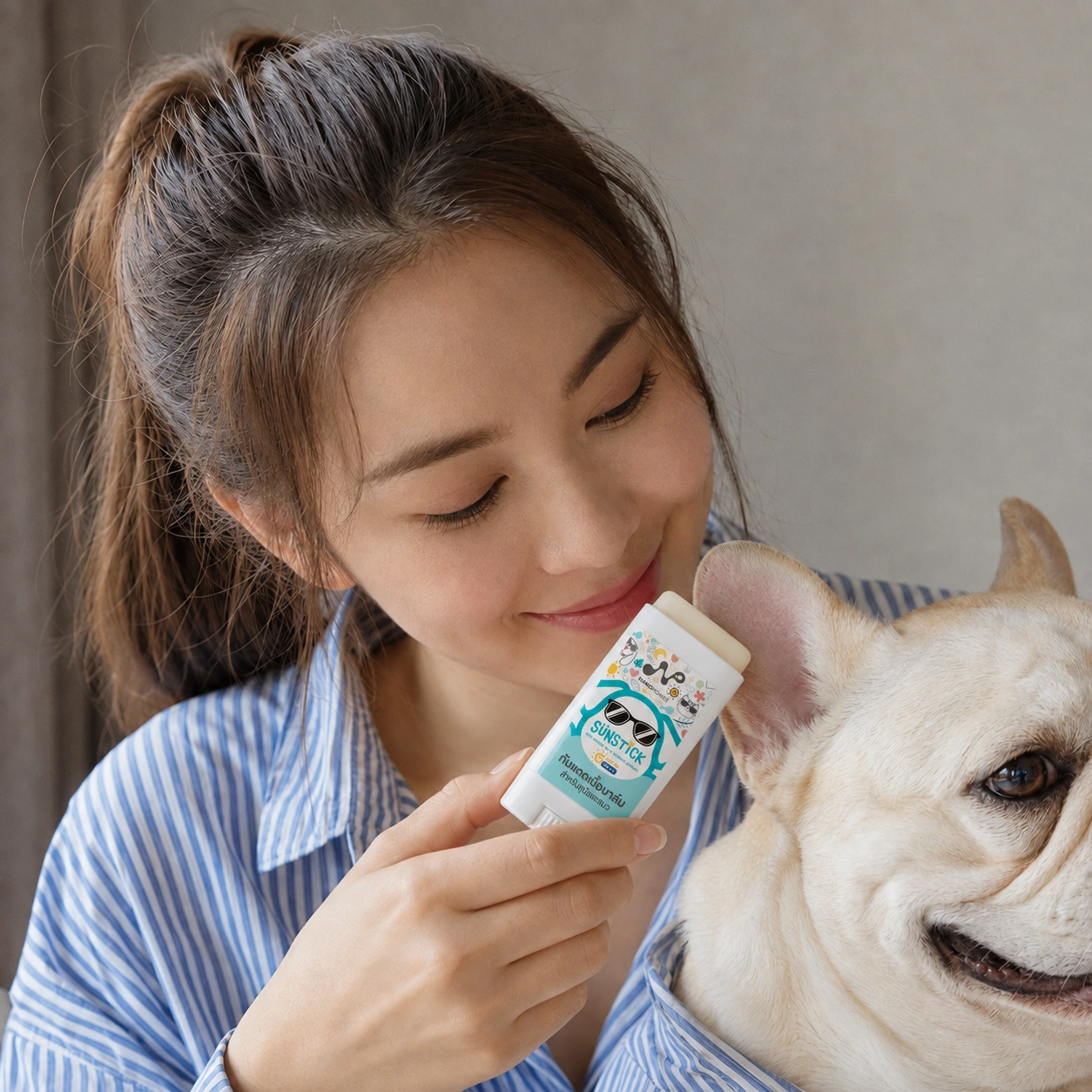 ผู้หญิงไทยจับแท่ง Sun Stick บริเวณด้านนอกใบหู French Bulldog